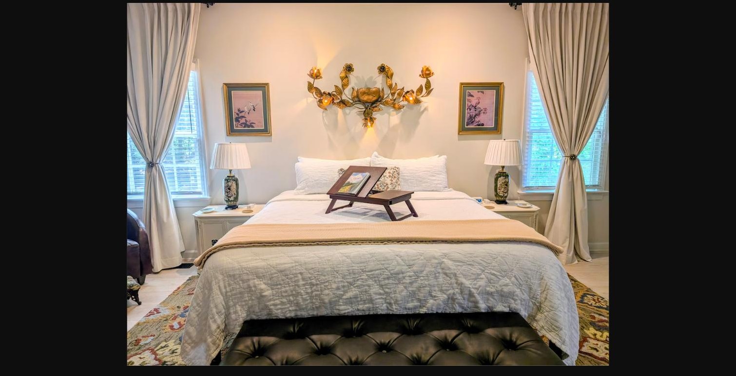 King bed with a breakfast tray, gilded floral sconce, and layered rug