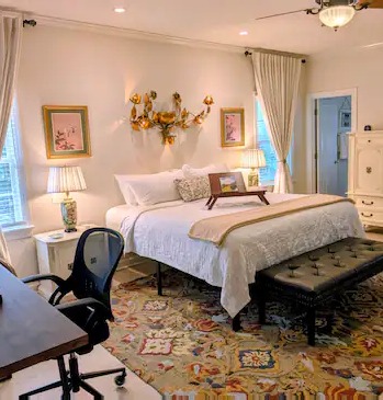 King bedroom with white linens and vintage floral art