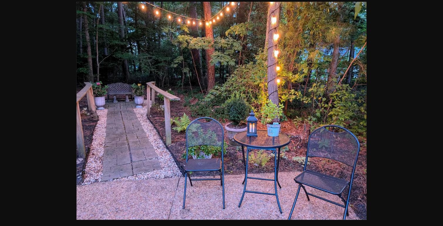 Bistro table and chairs along the string-lit garden path