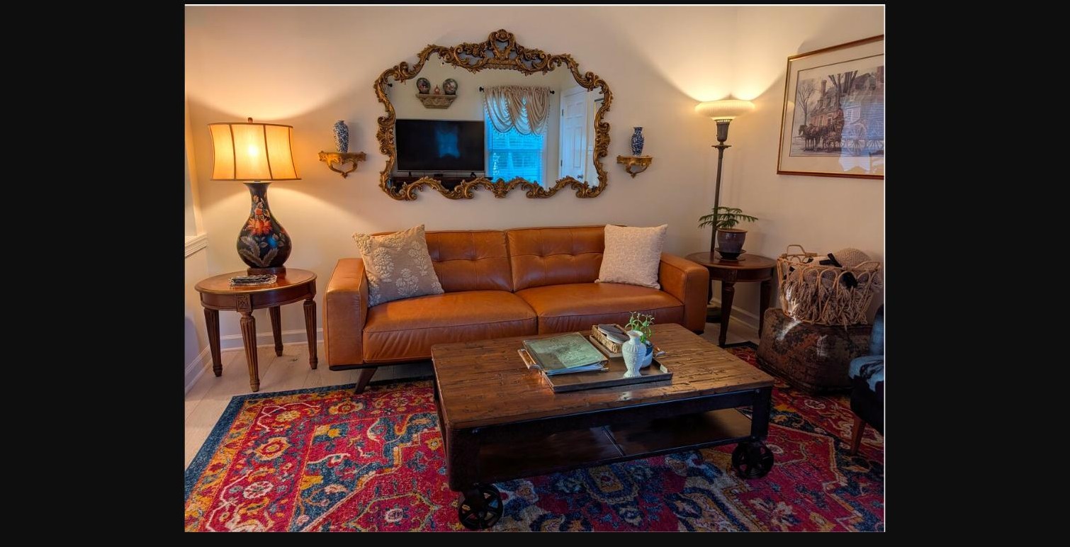 Living room seating area with a tufted leather sofa and ornate gold mirror