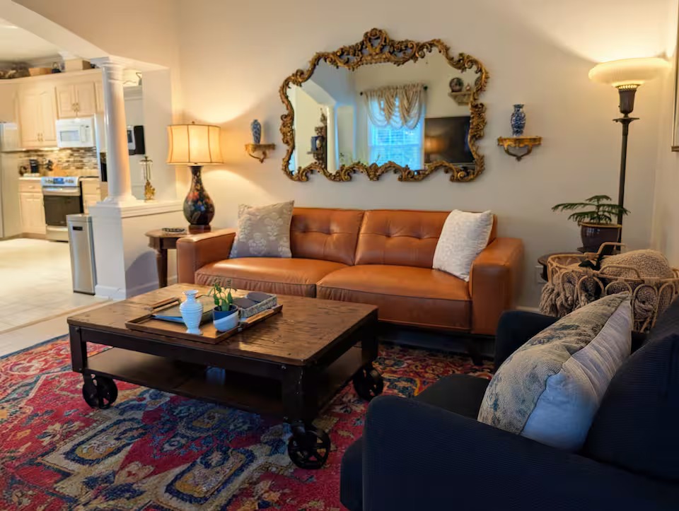 Warm, eclectic living room in the Granny Chic Suite with a leather sofa, antique gilded mirror, and layered vintage rug
